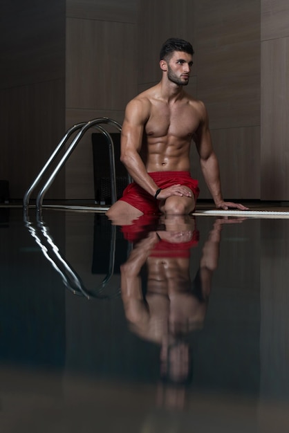 Heureux homme séduisant reposant détendu sur le bord de la piscine