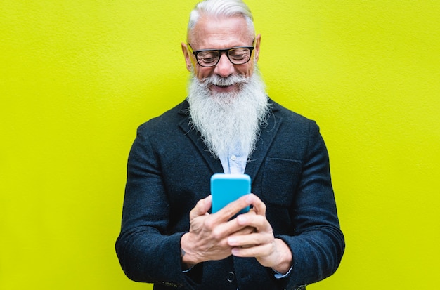 Heureux homme senior à l'aide de l'application smartphone avec couleur fluorescente. Vieil homme hipster s'amuser avec la technologie