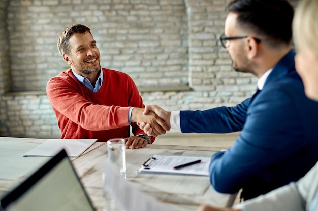 Heureux homme serrant la main d'un membre de l'équipe des ressources humaines lors d'un entretien d'embauche au bureau