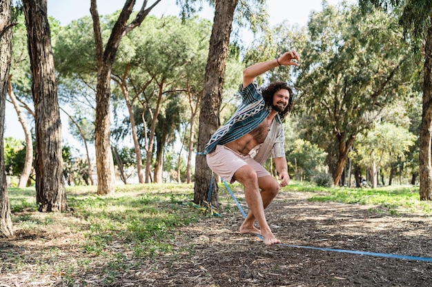 Heureux homme slackline dans le parc de la ville pendant la journée d'été