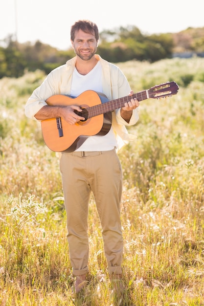 Heureux homme souriant à la caméra jouant de la guitare