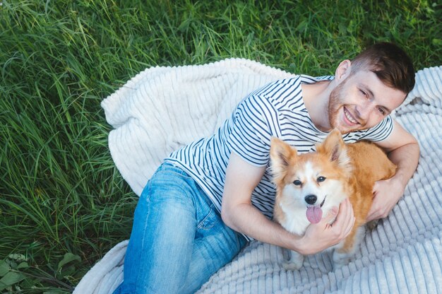 Heureux homme souriant avec son chien allongé sur l'herbe