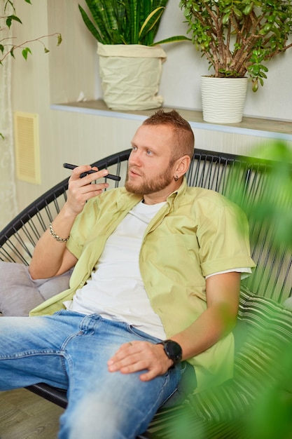 Heureux homme souriant tenant un téléphone portable parlant avec des amis ou en famille à l'aide d'un haut-parleur