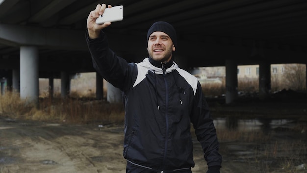 Heureux homme sportif prenant selfie portrait avec smartphone après une formation en plein air urbain