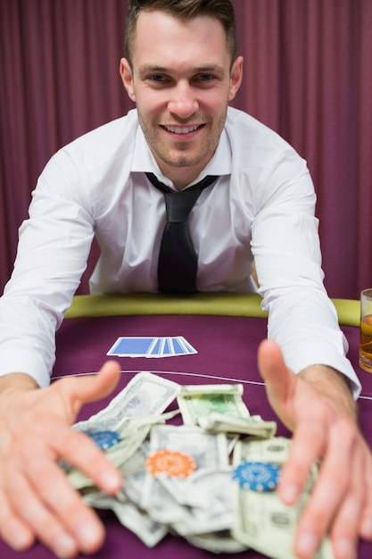 Heureux homme à la table de poker prenant ses gains