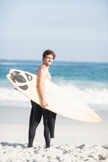 Heureux homme tenant une planche de surf sur la plage