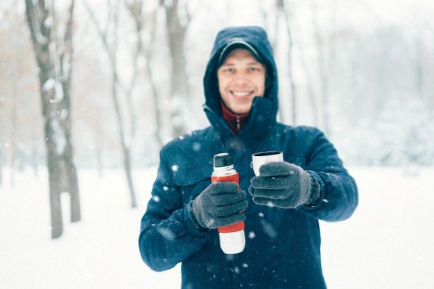 Heureux homme tenant un thermos à winter park