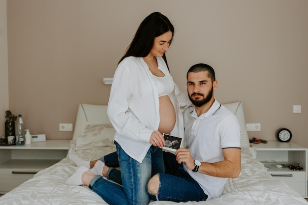 Heureux homme touchant le ventre d'une femme enceinte souriante allongée sur un canapé