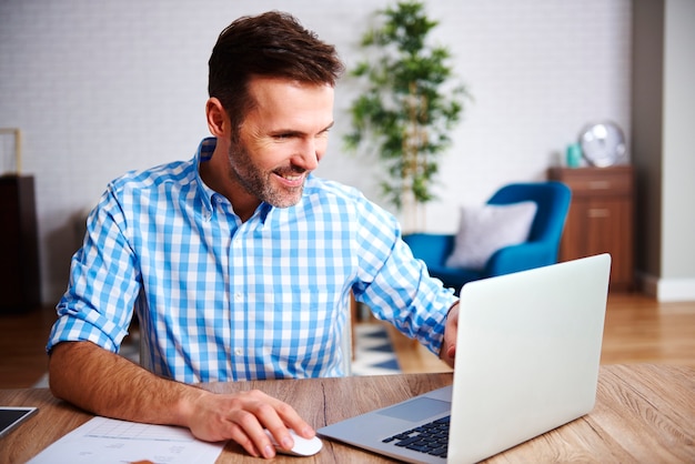 Heureux homme utilisant un ordinateur portable dans son bureau à domicile