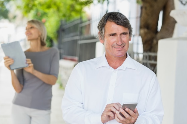 Heureux homme utilisant un téléphone portable avec une femme en arrière-plan