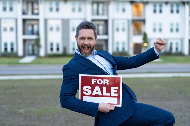 Photo heureux homme vendeur tenir conseil à vendre propriété vente propriété par vendeur en plein air