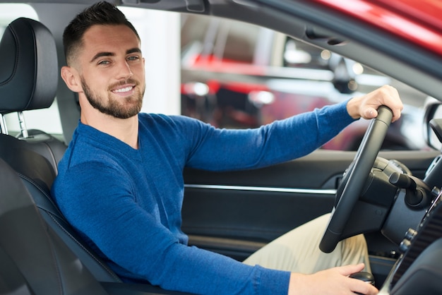 Photo heureux homme en voiture chez concessionnaire.