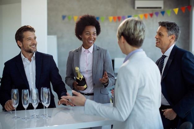 Heureux hommes d'affaires parlant tout en célébrant leur succès avec du champagne au bureau