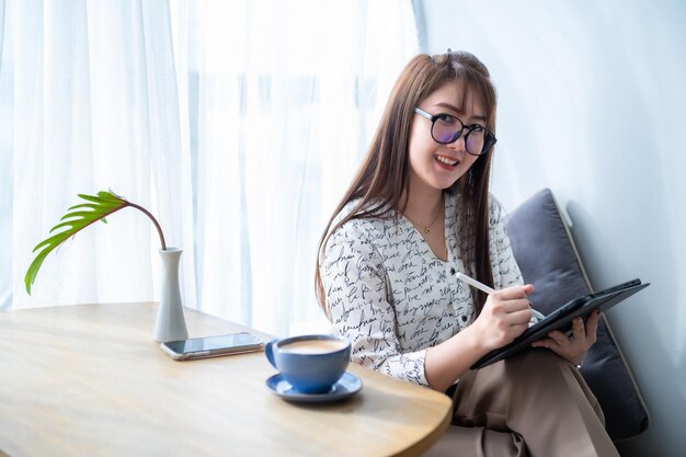 Heureux des indépendants asiatiques d'affaires féminins occasionnels travaillant avec Draw ou prenant note sur le numérique