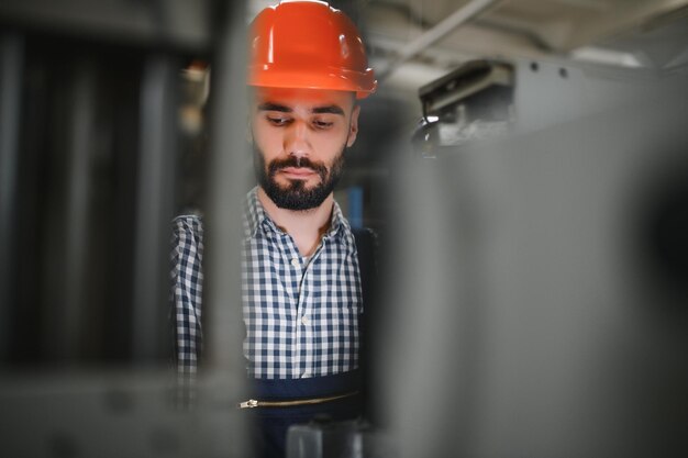 Heureux ingénieur professionnel de l'industrie lourde portant l'uniforme et un casque dans une aciérie Spécialiste industriel souriant debout dans une fabrication de construction métallique