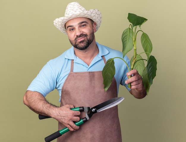 Heureux jardinier masculin de race blanche portant un chapeau de jardinage tenant une branche de plante et des ciseaux de jardinage