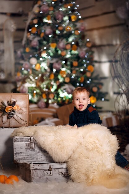 Heureux jeune bébé près de l'arbre de Noël avec des cadeaux et des mandarines