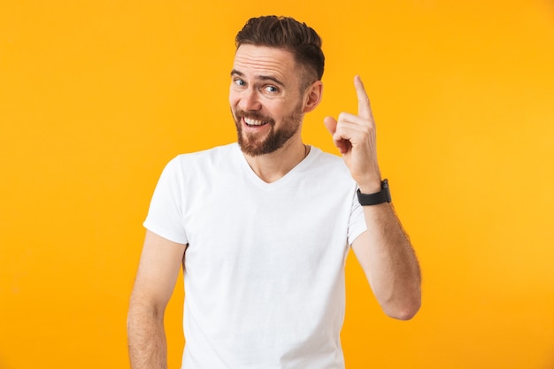 un heureux jeune bel homme posant isolé sur un mur jaune