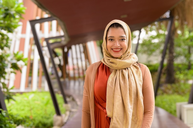 Heureux jeune belle femme musulmane indienne souriant dans la ville avec la nature