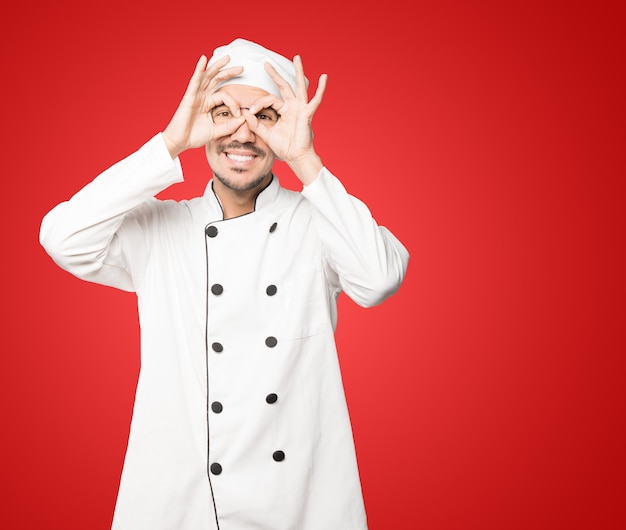 Heureux jeune chef à l'aide de ses mains comme des jumelles