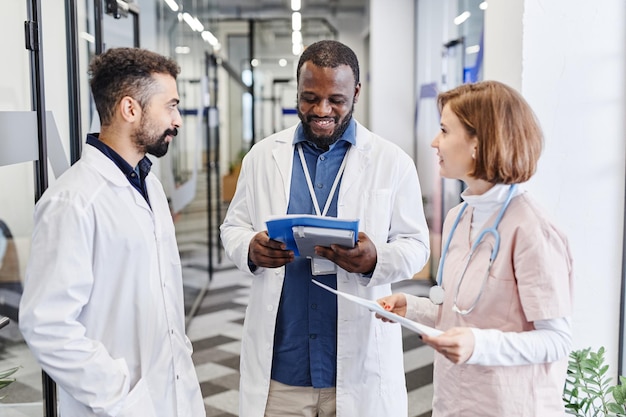 Heureux jeune clinicien afro-américain regardant à travers la forme médicale du patient