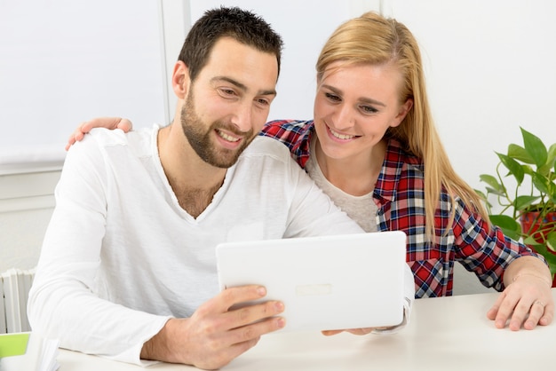 Photo heureux jeune couple à l'aide de tablette numérique