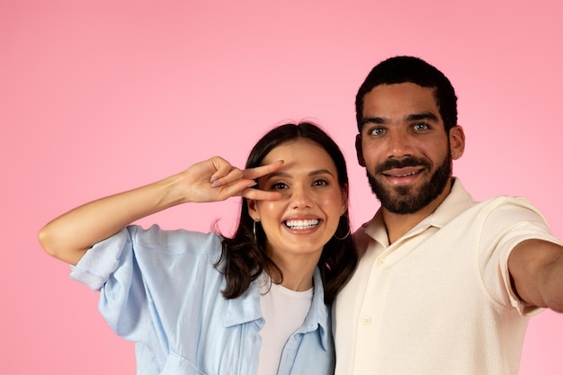 Heureux jeune couple aimant s'amuser sur rose en prenant selfie