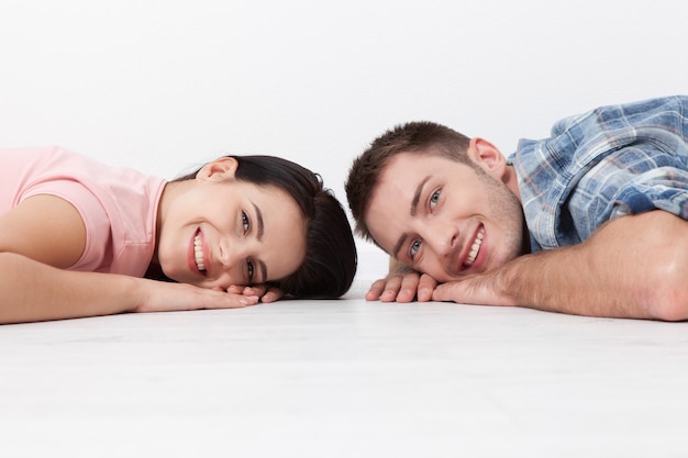 Heureux jeune couple allongé sur le sol, regardant et souriant