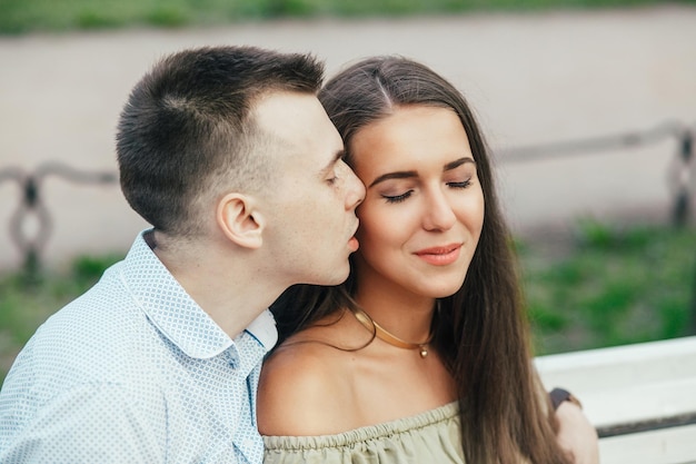 Heureux jeune couple amoureux assis sur un banc de parc et étreindre