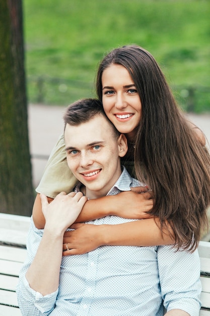 Heureux jeune couple amoureux assis sur un banc de parc et étreindre