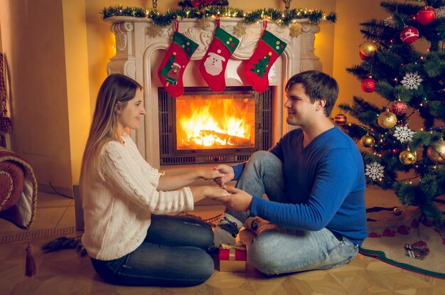 Heureux jeune couple amoureux assis à la cheminée et main dans la main