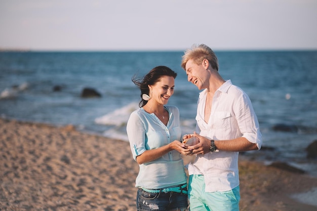 Heureux jeune couple amoureux contre la mer marcher sur la plage contre le ciel bleu et s'amuser le jour d'été
