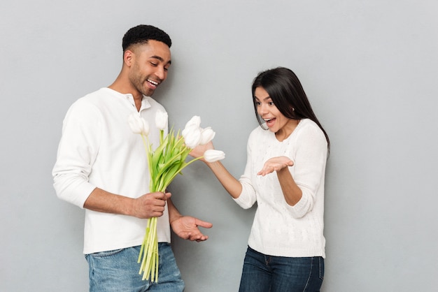 Heureux jeune couple d'amoureux debout sur le mur gris.