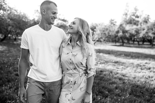 Heureux jeune couple amoureux étreignant jouit de la journée de printemps, aimant sans soucis ensemble à l'extérieur en marchant au parc