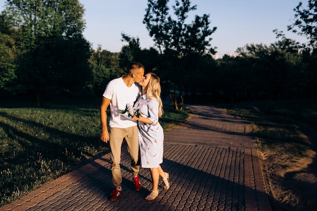 Heureux jeune couple amoureux étreignant jouit de la journée de printemps, aimant sans soucis ensemble à l'extérieur en marchant au parc