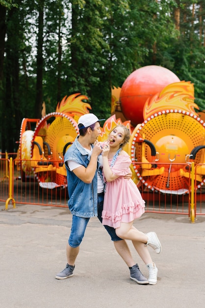 Heureux jeune couple amoureux s'amuser dans un parc d'attractions et danser