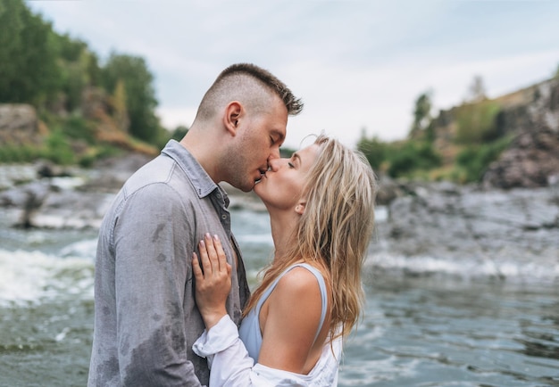 Heureux jeune couple amoureux voyageurs s'embrassant dans la rivière de montagne