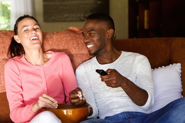 Heureux jeune couple appréciant regarder un film à la maison