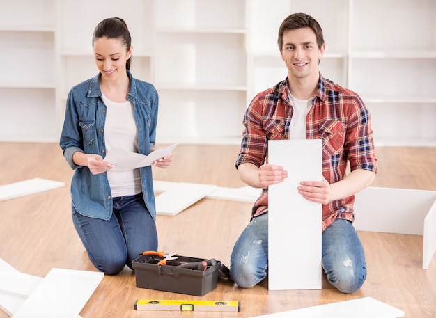 Heureux jeune couple assemblant des meubles à monter soi-même.