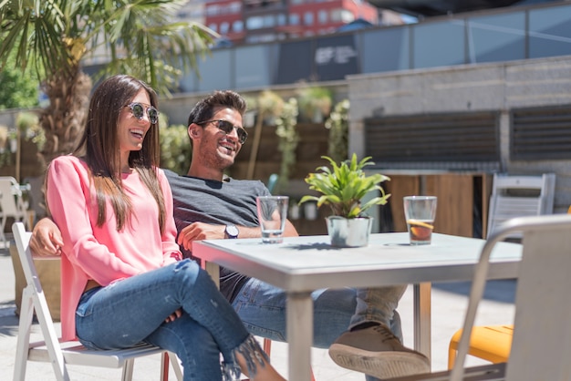 Heureux jeune couple assis détendu dans une terrasse de restaurant