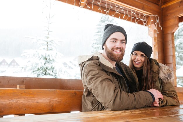 Heureux jeune couple assis ensemble à la table en bois