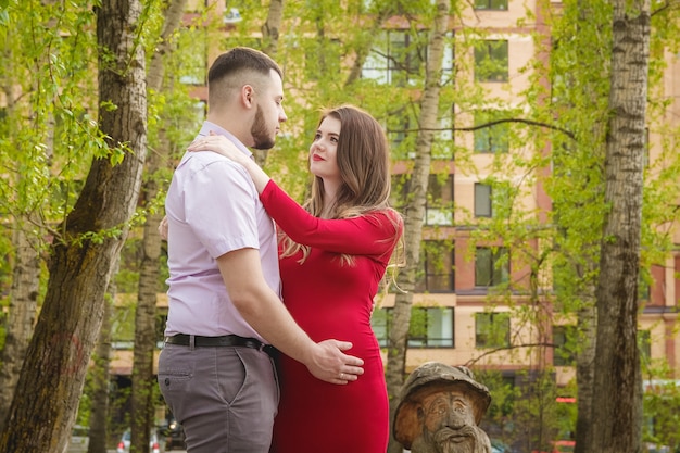 Heureux jeune couple attend bébé dans le parc d'été