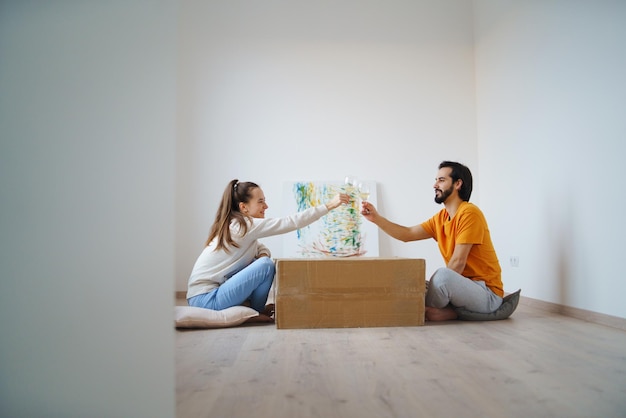 Heureux jeune couple avec des boîtes et du vin se déplaçant dans un nouvel appartement, un nouveau concept de maison et de réinstallation.