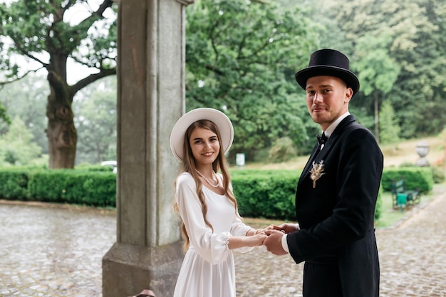 Heureux jeune couple Brides in hats Jeune fille dans une robe de mariée blanche et un chapeau avec un bouquet de fleurs Brides in the castle Bride and groom