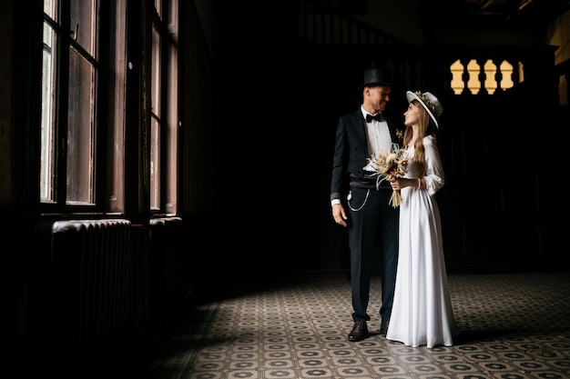 Heureux jeune couple Brides in hats Jeune fille dans une robe de mariée blanche et un chapeau avec un bouquet de fleurs Brides in the castle Bride and groom