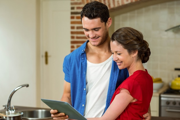 Heureux jeune couple cherche à tablette numérique dans la cuisine