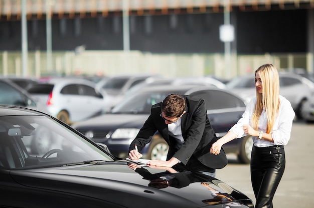 Heureux jeune couple choisit et achète une nouvelle voiture pour la famille