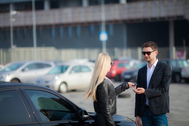 Heureux jeune couple choisit et achète une nouvelle voiture pour la famille.