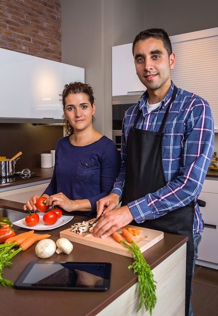 Heureux jeune couple dans une cuisine à domicile préparant des aliments sains pour le déjeuner. Concept de mode de vie familial moderne.