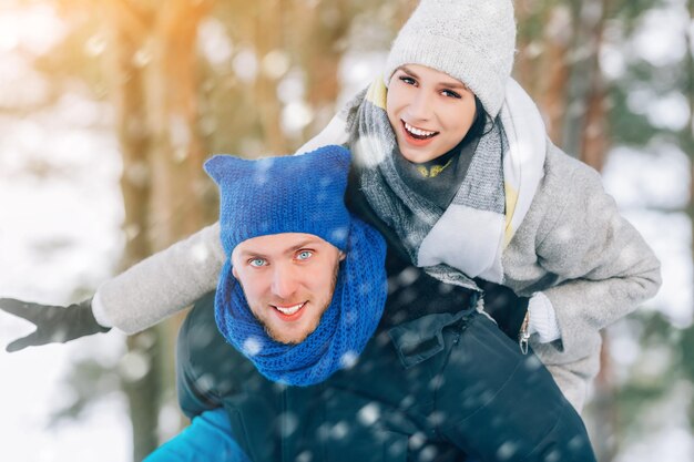 Heureux jeune couple dans le parc d'hiver en riant et en s'amusant en famille à l'extérieur